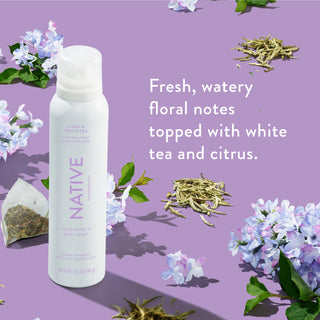 Native deodorant spray with text saying "Fresh, watery floral notes topped with white tea and citrus", styled with lilac bouquet