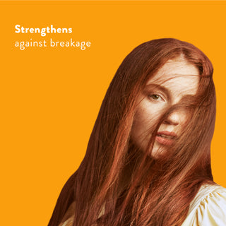 Woman with long red hair against an orange background with text reading “Strengthens against breakage”