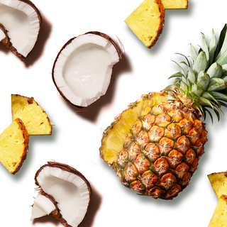 Pineapple sliced in half, styled with coconut halves and pineapple pieces