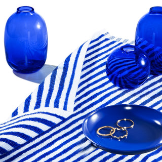 Plate with jewelry, blue glass vessels, and a striped towel