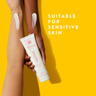 Hand holding Native Mineral Suncare Body Sunscreen SPF 30 with swatches on two arms promoting "Suitable for sensitive skin"