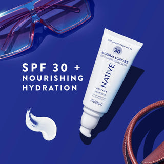 Tube of Native Mineral Suncare Daily Face Sunscreen SPF 30 next to a swatch of product, sunglasses, and a blue background